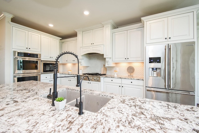 19019 Kimber Creek Ln, Cypress, TX 77429 - kitchen featuring stainless steel appliances, light stone counters, recessed lighting, decorative backsplash, and a sink