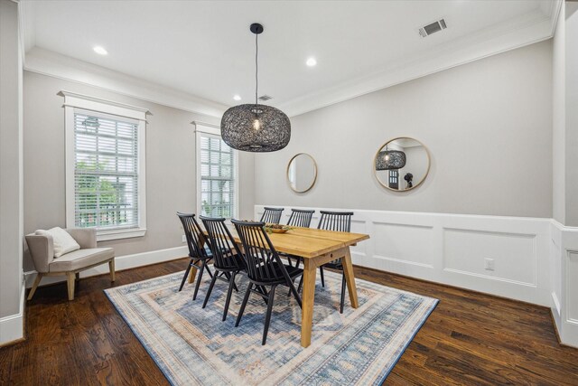 dining room featuring wainscoting, dark wood-style flooring, visible vents, and ornamental molding