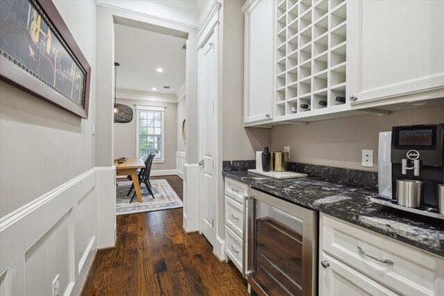 bar with ornamental molding, beverage cooler, dark wood-style floors, recessed lighting, and a bar