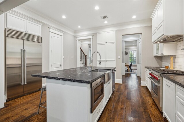 kitchen featuring built in appliances, visible vents, ornamental molding, and a sink