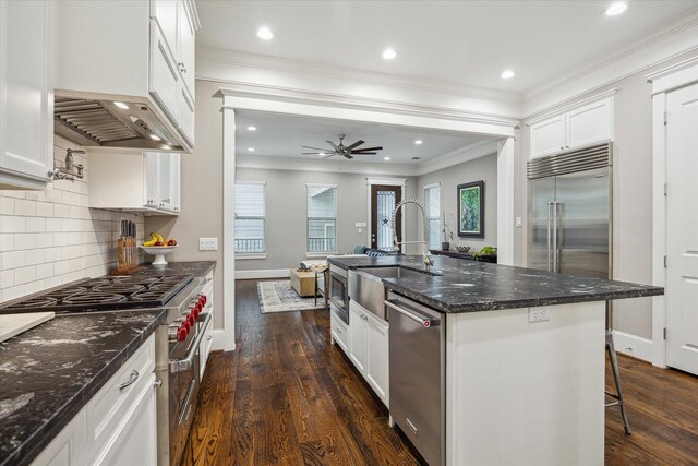 kitchen with a sink, high end appliances, decorative backsplash, and dark wood-style floors