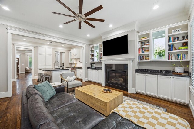 living room with crown molding, a ceiling fan, and dark wood-type flooring
