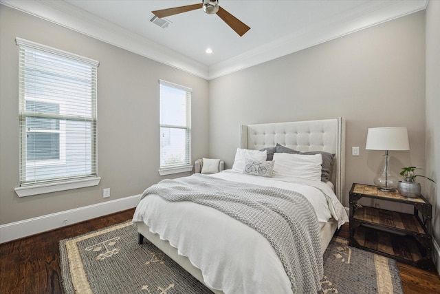 bedroom featuring ceiling fan, visible vents, wood finished floors, baseboards, and ornamental molding