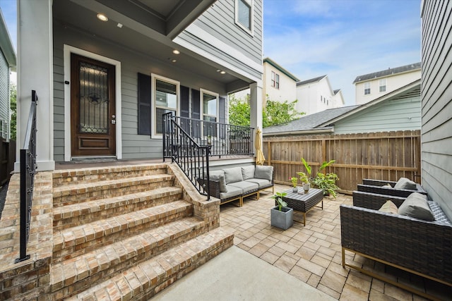 entrance to property featuring covered porch, fence, and an outdoor living space