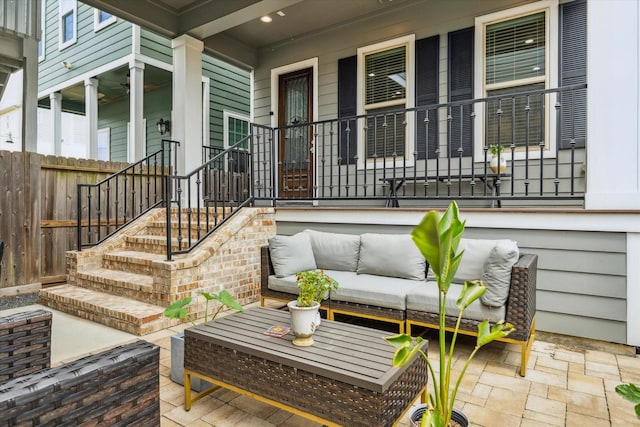 view of patio with an outdoor living space, fence, and covered porch
