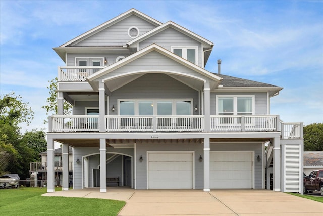raised beach house with concrete driveway, an attached garage, a balcony, and a front lawn