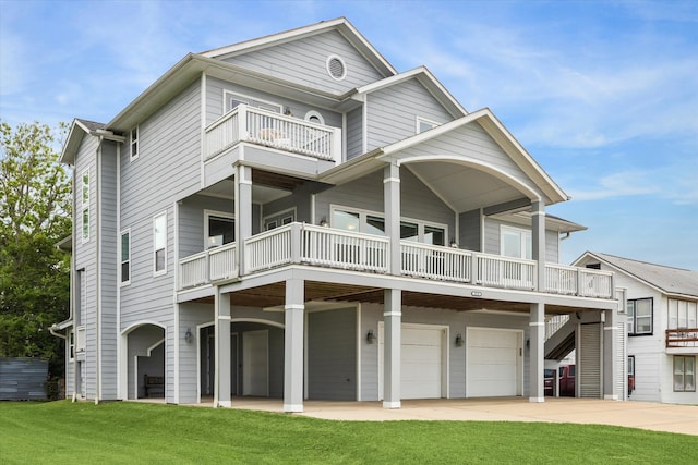 rear view of house with stairs, a garage, a balcony, a yard, and driveway