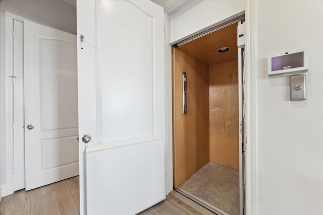 hallway featuring light wood-type flooring and elevator