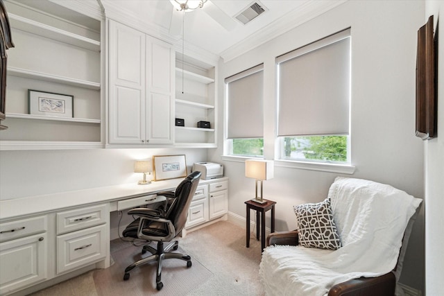 home office featuring visible vents, built in desk, baseboards, ornamental molding, and light carpet