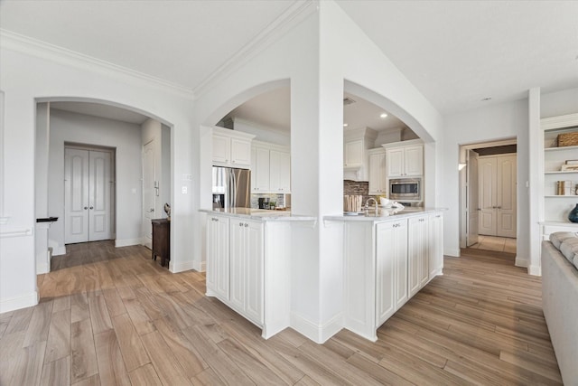 kitchen with light countertops, stainless steel appliances, light wood-style flooring, and white cabinetry