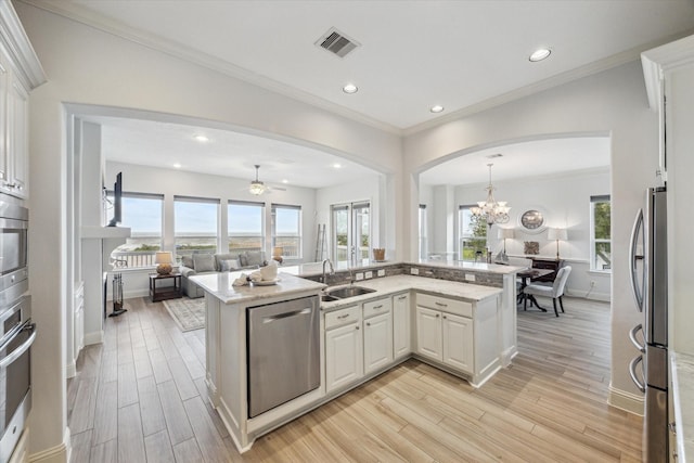 kitchen with visible vents, arched walkways, light wood-type flooring, a sink, and stainless steel appliances