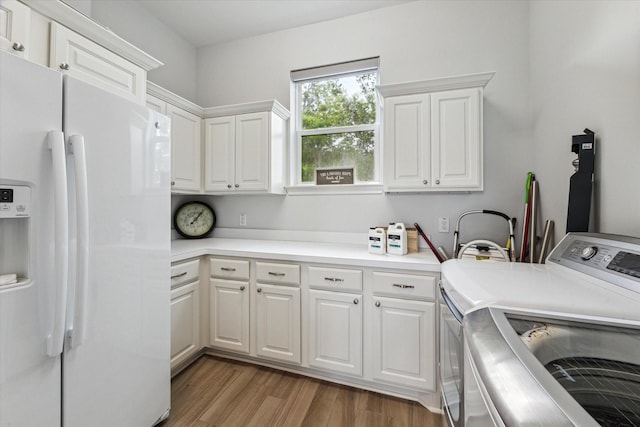 clothes washing area with light wood-style flooring, cabinet space, and washing machine and dryer