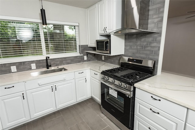 kitchen with decorative backsplash, white cabinetry, a sink, stainless steel appliances, and wall chimney exhaust hood