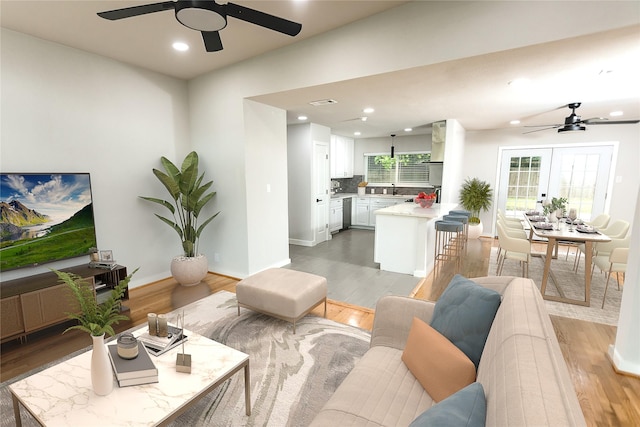 living area with recessed lighting, baseboards, a ceiling fan, and light wood-type flooring