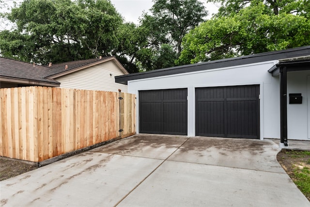 garage featuring fence and driveway