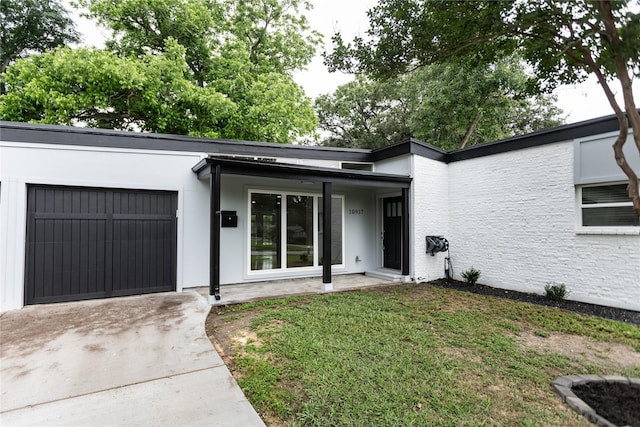 property entrance with a lawn, an attached garage, and driveway