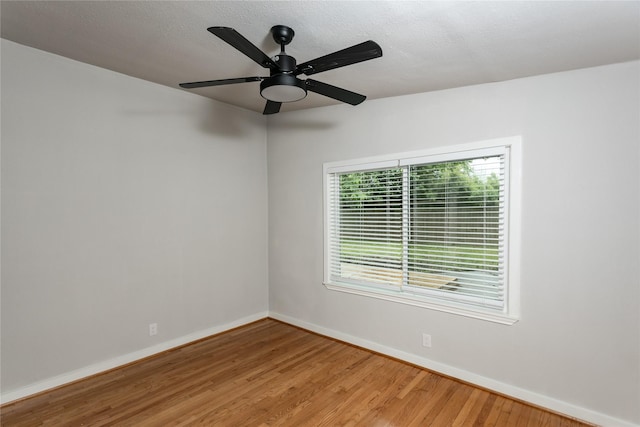 empty room with a ceiling fan, baseboards, plenty of natural light, and wood finished floors