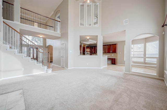 17931 Oakfield Glen Ln, Cypress, TX 77433 - unfurnished living room with visible vents, baseboards, a high ceiling, light colored carpet, and arched walkways
