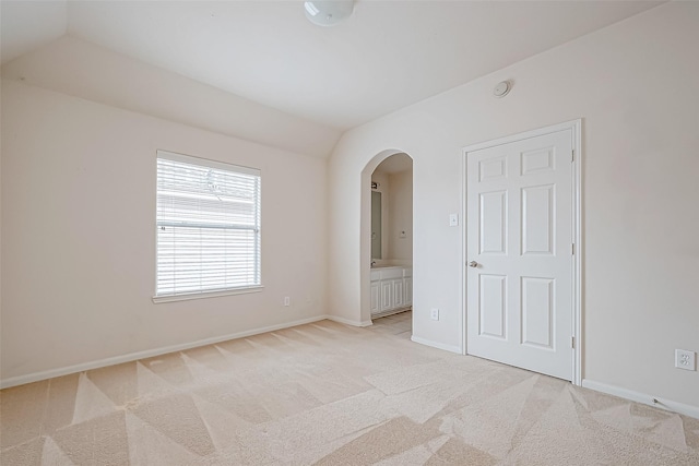 17931 Oakfield Glen Ln, Cypress, TX 77433 - unfurnished bedroom featuring light carpet, ensuite bath, arched walkways, baseboards, and lofted ceiling