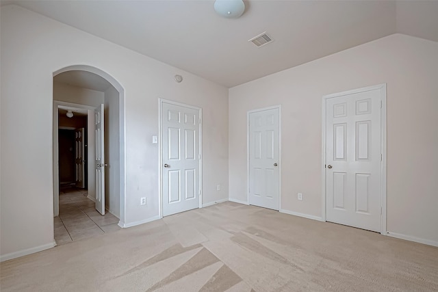 17931 Oakfield Glen Ln, Cypress, TX 77433 - unfurnished bedroom featuring arched walkways, baseboards, visible vents, and light carpet