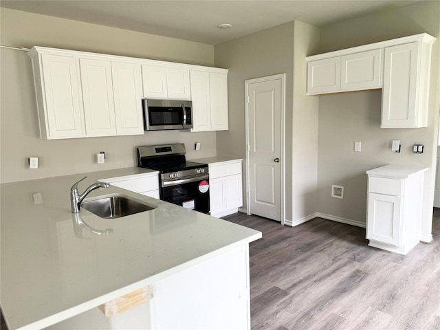 1563 Belton Ln, Anahuac, TX 77514 - kitchen featuring stainless steel appliances, a sink, light wood-type flooring, and white cabinets