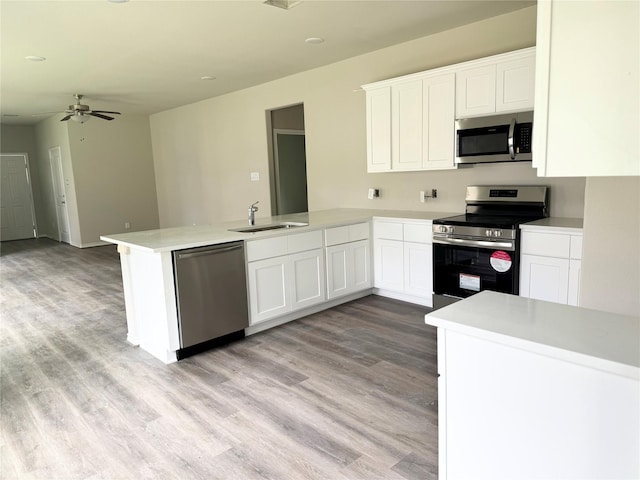 1563 Belton Ln, Anahuac, TX 77514 - kitchen featuring stainless steel appliances, a peninsula, a sink, and light wood-style flooring