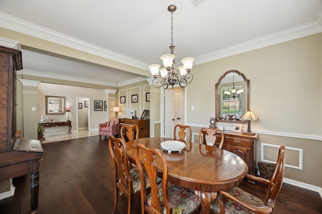 dining space with wood-type flooring, baseboards, crown molding, and a chandelier