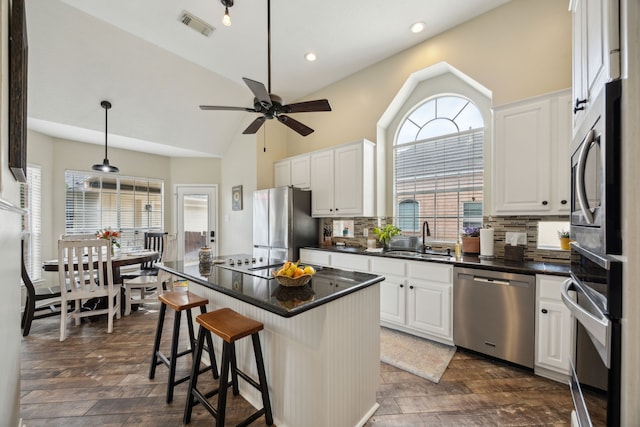 kitchen with visible vents, dark countertops, a sink, stainless steel appliances, and white cabinetry