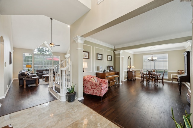living room featuring wood-type flooring, baseboards, ceiling fan with notable chandelier, and a healthy amount of sunlight