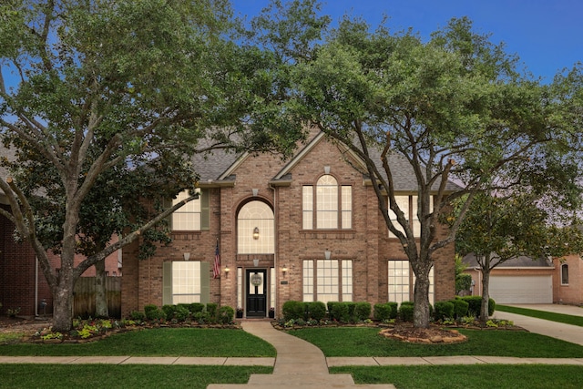 view of front of property with roof with shingles, a garage, brick siding, a front lawn, and concrete driveway