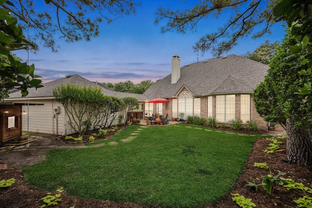 rear view of property featuring a lawn, a patio, and a chimney