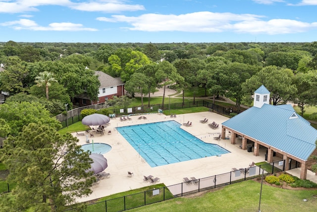 pool featuring a patio, fence, and a wooded view
