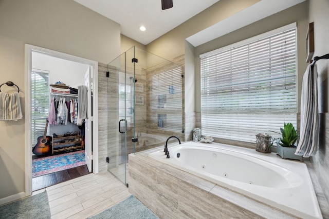full bath with a tub with jets, plenty of natural light, ceiling fan, and a stall shower