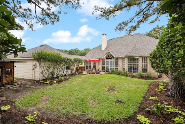 rear view of property with a patio area, a yard, and a chimney