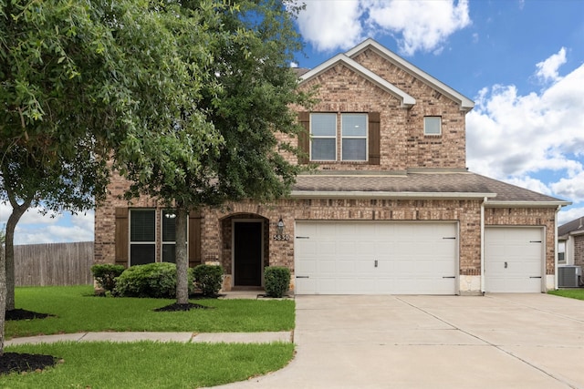 traditional-style home featuring fence, roof with shingles, brick siding, a front yard, and concrete driveway
