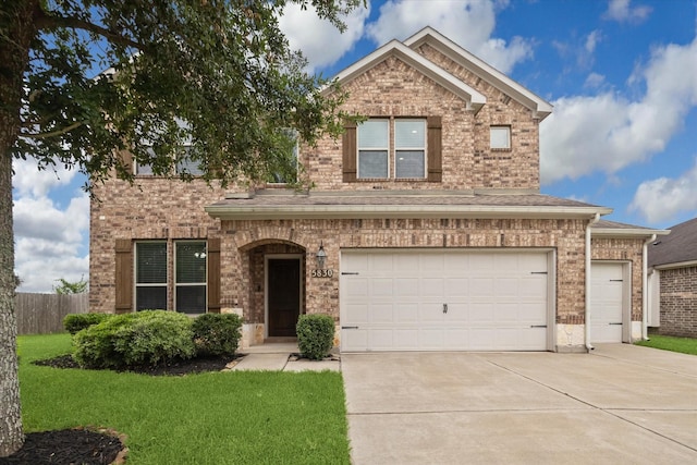 traditional-style house with a front yard, a garage, brick siding, fence, and concrete driveway