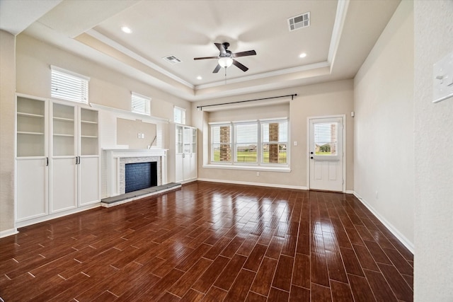 unfurnished living room featuring ceiling fan, a tray ceiling, wood finished floors, and visible vents