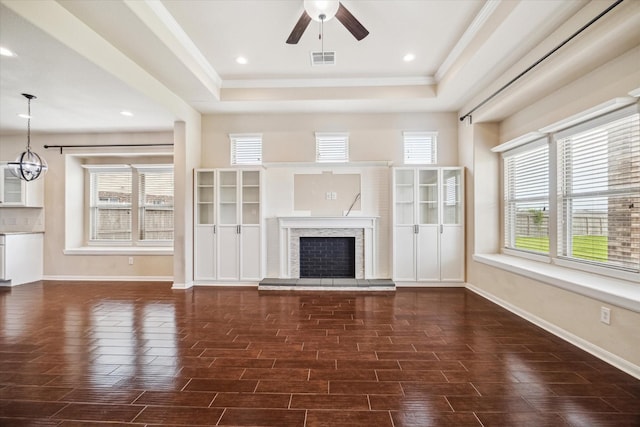 unfurnished living room featuring visible vents, baseboards, ceiling fan with notable chandelier, and a tray ceiling