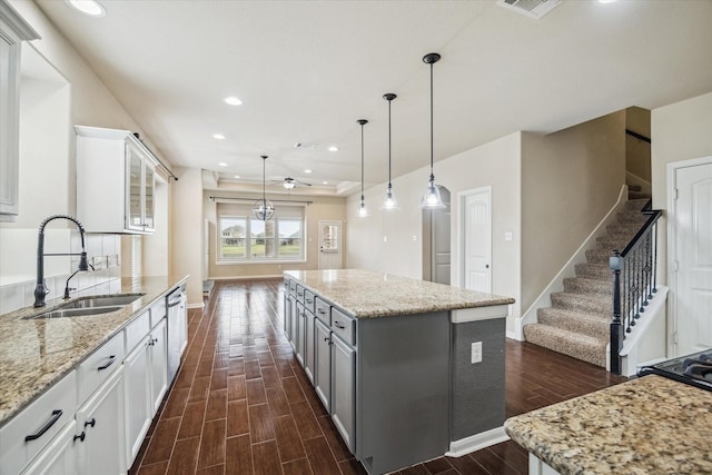 kitchen featuring a sink, dishwasher, dark wood finished floors, baseboards, and gray cabinetry