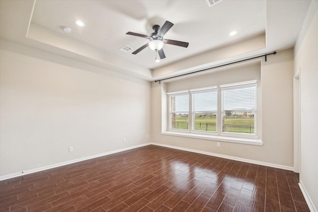 unfurnished room with baseboards, a ceiling fan, dark wood finished floors, and a tray ceiling