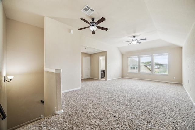 carpeted empty room featuring ceiling fan, attic access, baseboards, vaulted ceiling, and visible vents
