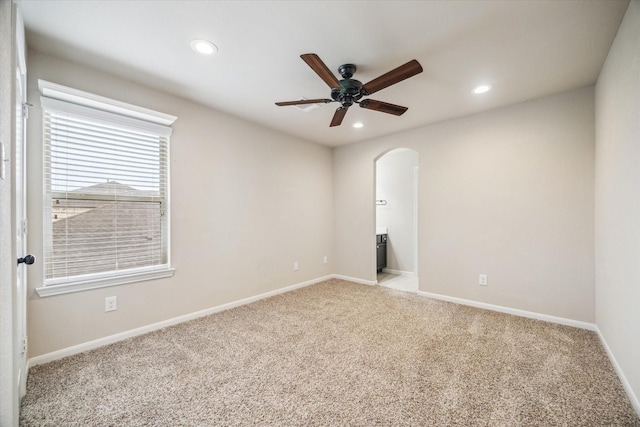 carpeted empty room featuring recessed lighting, arched walkways, baseboards, and ceiling fan