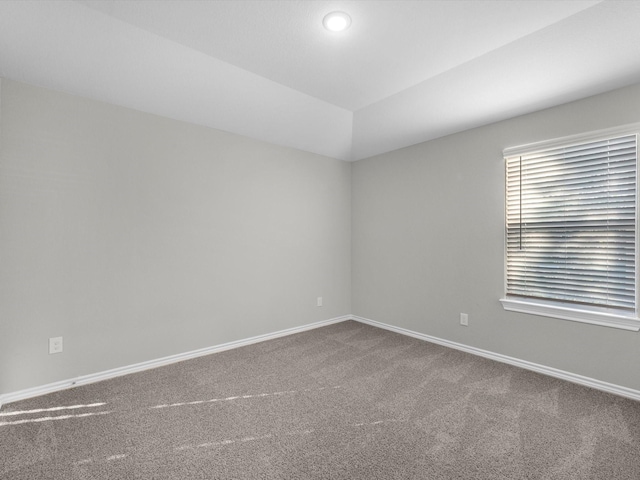 unfurnished room featuring vaulted ceiling, baseboards, and carpet flooring