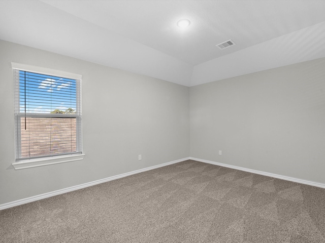 carpeted spare room featuring visible vents, baseboards, and lofted ceiling