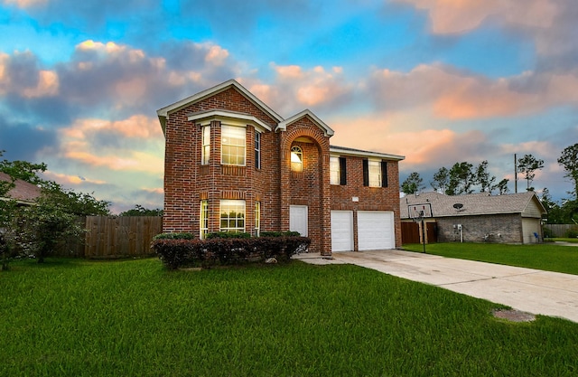 traditional-style home with a lawn, an attached garage, driveway, and brick siding