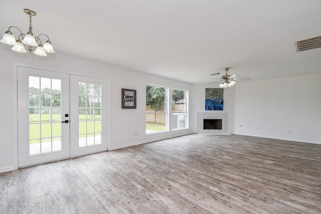 unfurnished living room with visible vents, wood finished floors, baseboards, french doors, and ceiling fan with notable chandelier