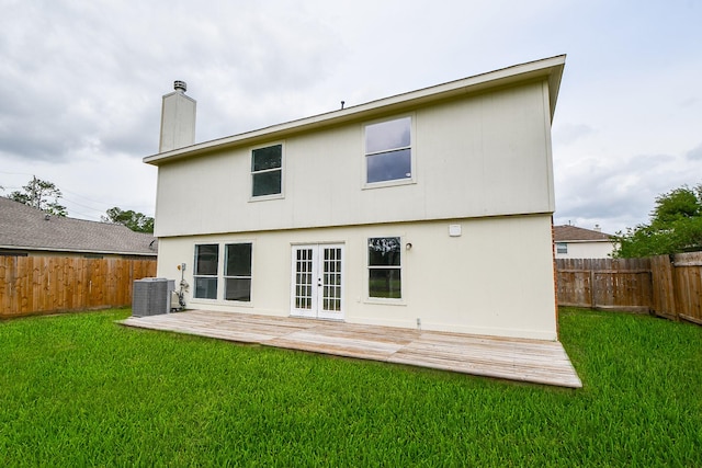 rear view of property featuring french doors, a lawn, cooling unit, and a fenced backyard