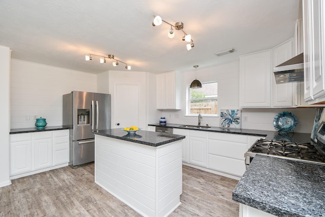 kitchen with wall chimney range hood, a sink, stainless steel appliances, light wood-type flooring, and visible vents