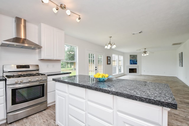 kitchen featuring visible vents, wall chimney exhaust hood, gas stove, and light wood-style floors