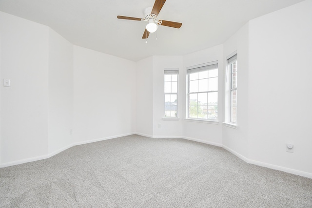 carpeted empty room with baseboards and a ceiling fan